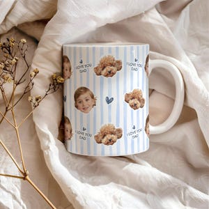 May include: A white ceramic mug with a blue and white striped pattern. The mug is decorated with images of a child's face, a dog's face, and the text "I LOVE YOU DAD". The mug has a white handle.