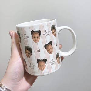 May include: White ceramic mug with a handle, decorated with images of children's faces, pink vertical stripes, and small heart shapes. The text "I LOVE YOU MOM" is repeated around the mug. A perfect gift for Mother's Day.