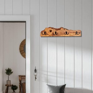 Olivenholz Wandgarderobe über einer Vintage Bank im skandinavischen Eingangsbereich.
