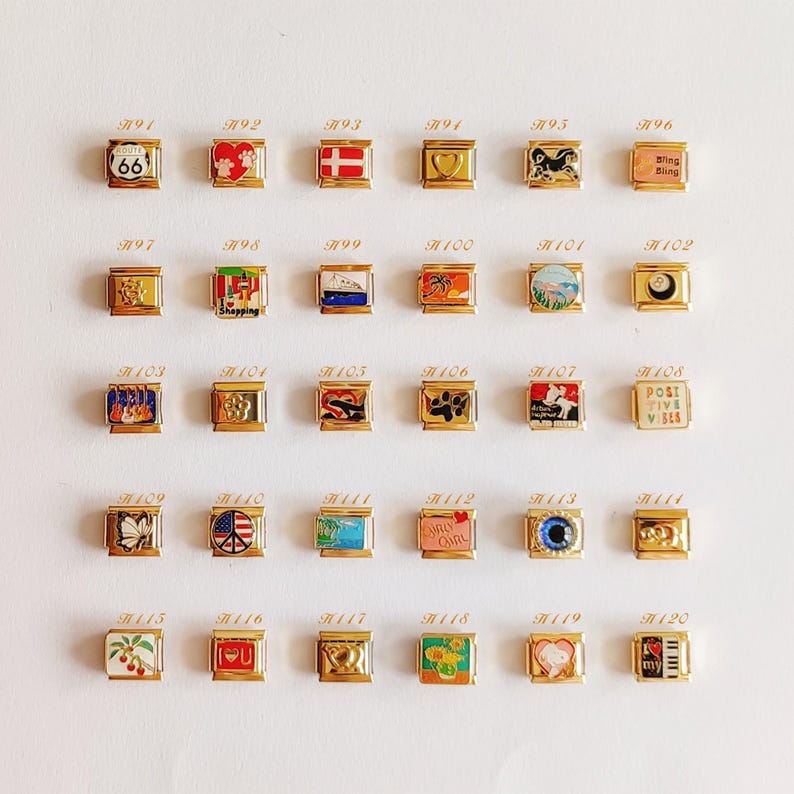 Puede incluir: Una colecci&oacute;n de treinta eslabones modulares dorados para pulsera dispuestos en cinco filas. Cada eslab&oacute;n cuadrado presenta un dise&ntilde;o de esmalte &uacute;nico, incluyendo s&iacute;mbolos como una se&ntilde;al de la Ruta 66, corazones, banderas, animales y texto.