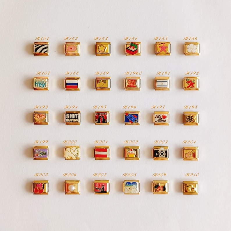 Puede incluir: Una colecci&oacute;n de treinta eslabones modulares para pulsera en tono dorado, dispuestos en cinco filas de seis. Cada eslab&oacute;n presenta un dise&ntilde;o &uacute;nico en esmalte o metal, incluyendo s&iacute;mbolos, banderas, textos como 'SHIT HAPPENS' y 'Be Mine'.