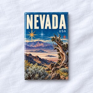 May include: A rectangular magnet featuring a landscape of Nevada, USA. The design shows desert mountains, a twisted tree, and desert shrubs under a blue sky with star icons. The word NEVADA is printed in large white letters at the top.