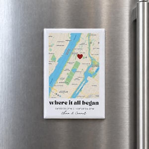 Peut inclure: Un aimant rectangulaire présentant une carte de Manhattan avec une icône de cœur rouge. Sous la carte, le texte indique where it all began, suivi des coordonnées 34°00'30.7"N | 118°29'56.0"W et des noms Elena & Connor en lettres noires.
