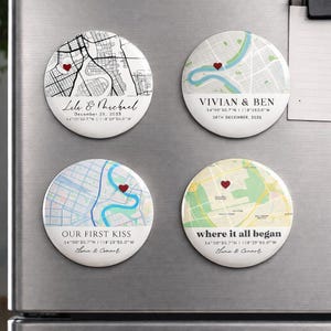 May include: Four round magnets with map designs and red heart accents. Each magnet features names, dates, and coordinates. The text includes phrases like "Lile & Michael," "Vivian & Ben," "Our First Kiss," and "where it all began."