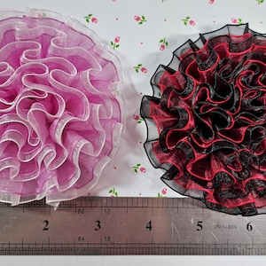 May include: Two fabric flowers, one pink and white, the other black and red, measuring approximately 2 inches in diameter.