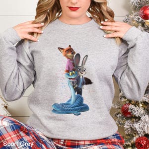 Peut inclure: Un sweat-shirt gris clair avec un graphisme color&eacute; de personnages anim&eacute;s. Le graphisme comprend un renard en chemise rose, un lapin en veste bleue et un serpent bleu. Les mots "Sport Grey" sont imprim&eacute;s en bas.