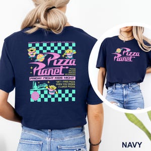 May include: Navy blue t-shirt featuring the text "Pizza Planet" in pink and a graphic of a planet with a pizza. The back of the shirt has a larger design with aliens, the words "Pizza Planet", and the text "Friday Night Kids Night".