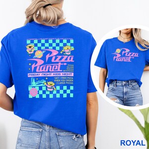 May include: Royal blue t-shirt featuring the Pizza Planet logo and alien characters. The back of the shirt has the text "Pizza Planet" with additional text about pizzas, salads, snacks, beverages, and Friday night kids night.