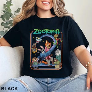 Pode incluir: Camiseta preta com um gr&aacute;fico colorido do filme de anima&ccedil;&atilde;o Zootopia. O design inclui o t&iacute;tulo do filme e v&aacute;rios personagens. A palavra "BLACK" est&aacute; impressa na parte inferior.