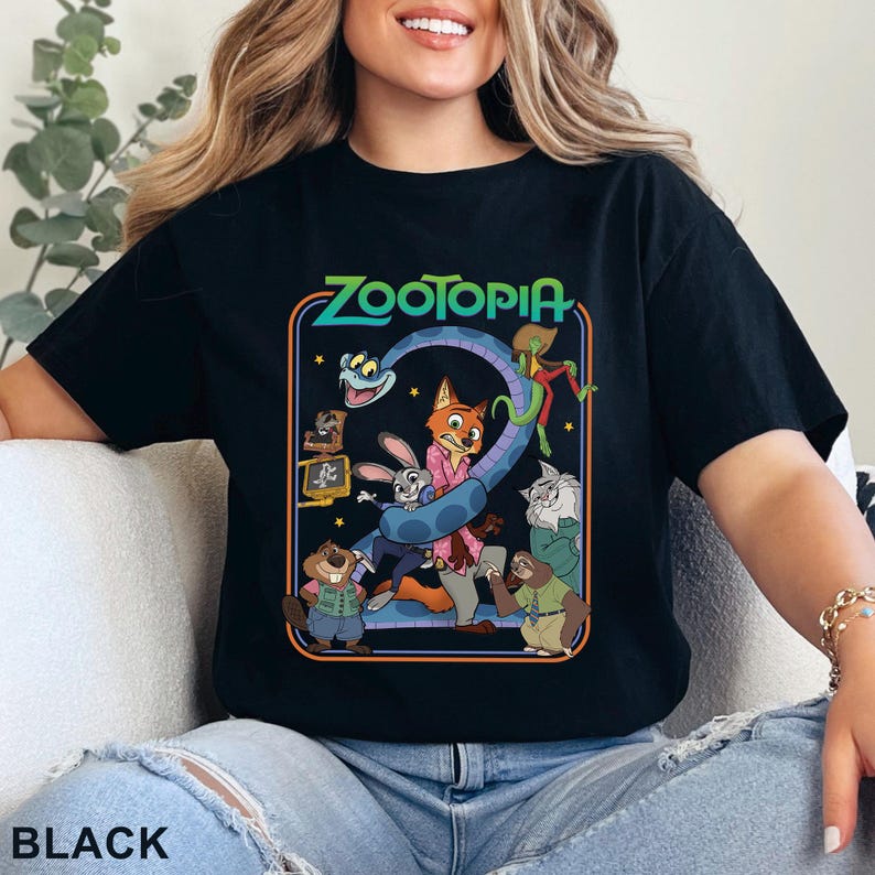 Pode incluir: Camiseta preta com um gr&aacute;fico colorido do filme de anima&ccedil;&atilde;o Zootopia. O design inclui o t&iacute;tulo do filme e v&aacute;rios personagens. A palavra "BLACK" est&aacute; impressa na parte inferior.