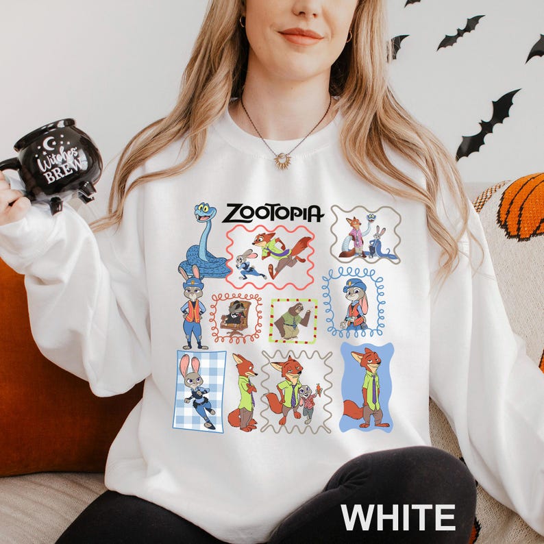 May include: White sweatshirt featuring a colorful collage of Zootopia characters. The word "Zootopia" is printed in black above the images. The word "WHITE" is printed in white at the bottom of the sweatshirt.