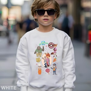 May include: White sweatshirt featuring characters from the animated movie "Zootopia". The design includes a sloth, fox, bunny, and other characters. The text "Zootopia 2" and "The Big Donut" are also visible. The sweatshirt is worn by a person wearing sunglasses.