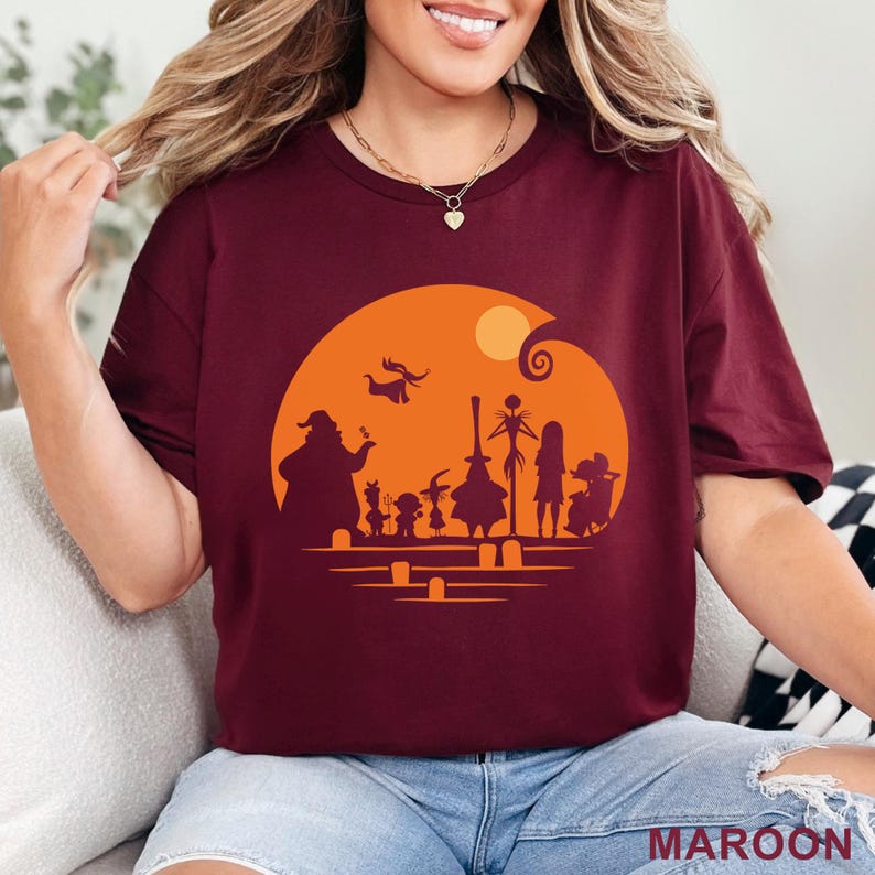 Pu&ograve; includere: T-shirt bordeaux con una silhouette di personaggi di un popolare film d'animazione su un cerchio arancione con una luna. Il testo "MAROON" &egrave; in basso. La maglietta &egrave; di colore bordeaux unito.