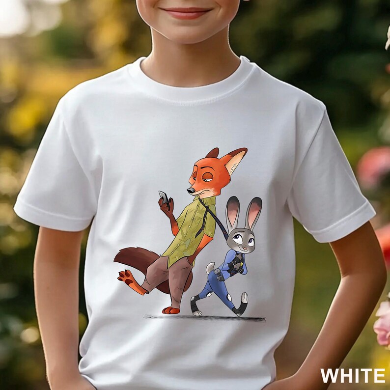 Pode incluir: Camiseta branca com uma ilustra&ccedil;&atilde;o de desenho animado de Nick Wilde e Judy Hopps de Zootopia. Nick, uma raposa laranja, est&aacute; segurando um telefone, enquanto Judy, uma coelha cinza, anda ao lado dele. A palavra "WHITE" est&aacute; impressa no canto inferior direito.