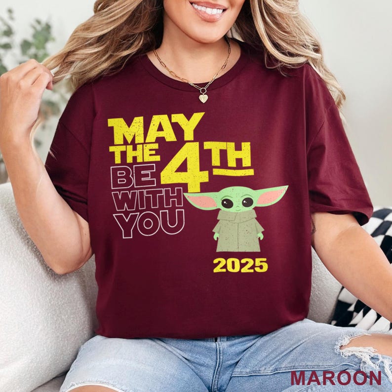 May include: A maroon t-shirt with a yellow graphic that says "May the 4th Be With You" and features a green cartoon character. The year 2025 is printed below the character.