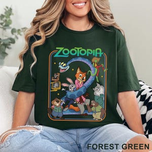 Pode incluir: Camiseta verde floresta com um gr&aacute;fico colorido do filme Zootopia. O design inclui o t&iacute;tulo do filme e v&aacute;rios personagens animais. A camiseta tem gola redonda e mangas curtas.