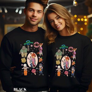 May include: Black sweatshirts featuring a colorful graphic of characters from the animated film Zootopia. The design includes a sloth, fox, rabbit, and other characters, along with the text "Zootopia" and "The Big Donut".