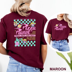 May include: Maroon t-shirt featuring the Pizza Planet logo and graphics. The design includes the text "Pizza Planet", "Pizzas, Salads, Snacks, Beverages", and "Friday Night Kids Night". The shirt also has a graphic of a space alien.
