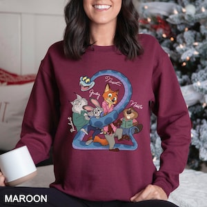 May include: Maroon sweatshirt with a cartoon graphic of characters from a movie. The graphic includes a blue snake with the number 2, and the names "Judy", "Nick", and "Nibbles". The word "MAROON" is printed at the bottom.