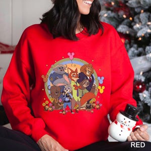 May include: A red sweatshirt with a cartoon graphic of animal characters in a circular design. The graphic includes a rainbow, flowers, and Mickey Mouse-shaped balloons. The word "RED" is printed at the bottom of the sweatshirt.