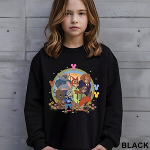 May include: Black sweatshirt with a vibrant cartoon illustration of animal characters, including a fox and lion, set within a circular design with a rainbow and stars. The word "BLACK" is printed at the bottom right of the garment.