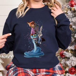 Peut inclure: Sweat-shirt bleu marine avec un motif color&eacute; de personnages du film d'animation Zootopie. Le motif comprend un renard, un lapin et un serpent. Le mot "NAVY" est imprim&eacute; sur le c&ocirc;t&eacute; gauche du sweat-shirt.