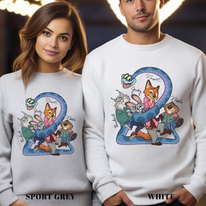 May include: Sport grey and white sweatshirts with a cartoon animal design. The illustration includes a blue snake, a fox, a rabbit, a beaver, and a cat. The text "Judy", "Nick", and "Nibbles" is also visible on the sweatshirts.