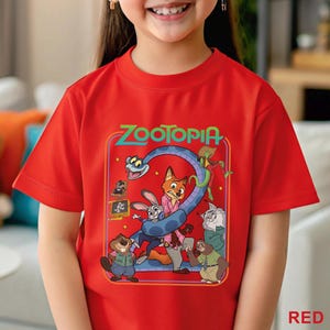 Pode incluir: Uma camiseta vermelha com a palavra "Zootopia" em verde e um gr&aacute;fico colorido de personagens do filme de anima&ccedil;&atilde;o. O gr&aacute;fico inclui uma cobra, uma raposa, um coelho e outros personagens animais.