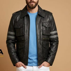 May include: A black leather jacket with a collar, four front pockets, and two grey stripes on each sleeve. The jacket is worn over a light blue t-shirt and white trousers. The logo for Rivera Enterprises is visible on the left side of the image.