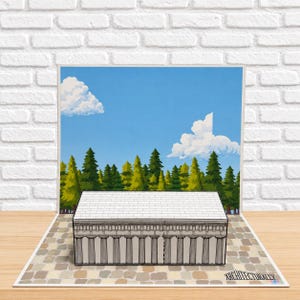 May include: A pop-up card featuring a three-dimensional paper model of a rectangular building with columns and a tiled roof. The background shows a printed illustration of a forest under a blue sky with white clouds. The text ARCHITECTURALLY is visible.