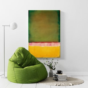 Può includere: Un dipinto astratto in tonalità di verde, giallo e rosa è appeso a una parete bianca sopra una poltrona sacco verde. Una piccola pianta in vaso e una pila di libri sono su un tappeto bianco davanti alla poltrona.
