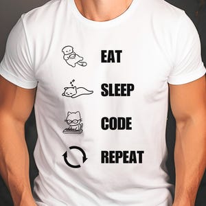 May include: White t-shirt with a black graphic that says "Eat, Sleep, Code, Repeat" with a cartoon cat illustration for each activity.