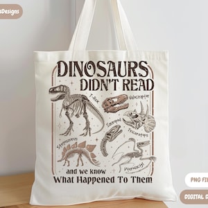 May include: Cream-colored tote bag featuring a dinosaur-themed design. The design includes dinosaur skeletons and the text "DINOSAURS DIDN'T READ and we know What Happened To Them". The bag has two handles and is made of a canvas-like material.