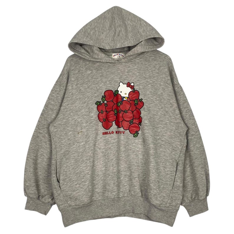 May include: A gray hooded sweatshirt with a Hello Kitty graphic. Hello Kitty is surrounded by red apples and the text "Hello Kitty" is printed below the graphic.