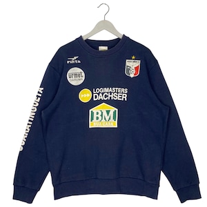 Puede incluir: Sudadera azul marino con múltiples logotipos y texto. Los logotipos incluyen "Pinta", "Urmet Daruma", "Logimasters Dachser" y "BM Sua Casa". El texto "Guaratingueta" está impreso en la manga izquierda. La sudadera está colgada de una percha blanca.