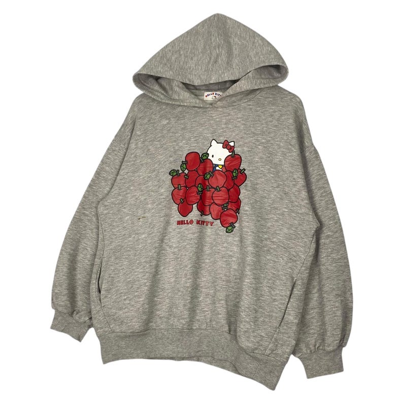 May include: A gray hooded sweatshirt with a Hello Kitty graphic. The graphic features Hello Kitty holding a bunch of red apples.