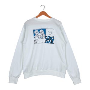 May include: White long-sleeve sweatshirt with a blue and white graphic print on the back. The graphic features three anime characters and the text "MUSIC: " followed by a list of names. The text "NEXT PHASE" is printed in a blue square in the upper right corner of the graphic.