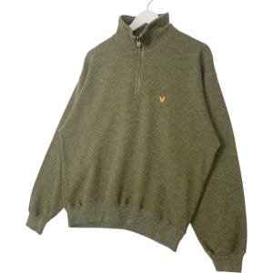 Puede incluir: Sudadera verde oliva con cierre de cremallera de un cuarto y un peque&ntilde;o logotipo amarillo en el pecho. La parte superior de manga larga est&aacute; hecha de un material suave y tiene dobladillo y pu&ntilde;os acanalados. La sudadera est&aacute; colgada en una percha blanca.