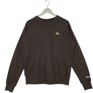 May include: Dark brown sweatshirt with a crew neck and long sleeves. A small, tan triangle logo is on the chest. The word "KELTY" is printed in white on the left sleeve cuff. The sweatshirt is hanging on a white hanger.