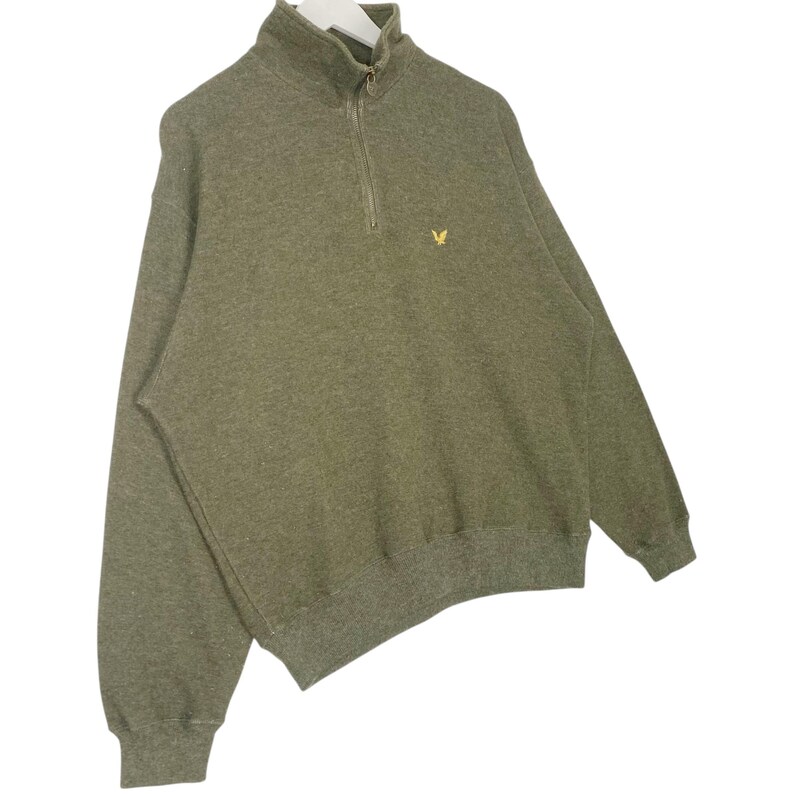 Puede incluir: Sudadera verde oliva con cierre de cremallera de cuarto de cuello y un peque&ntilde;o logotipo amarillo en el pecho. La parte superior de manga larga tiene cuello y pu&ntilde;os acanalados. Estilo casual para uso diario.