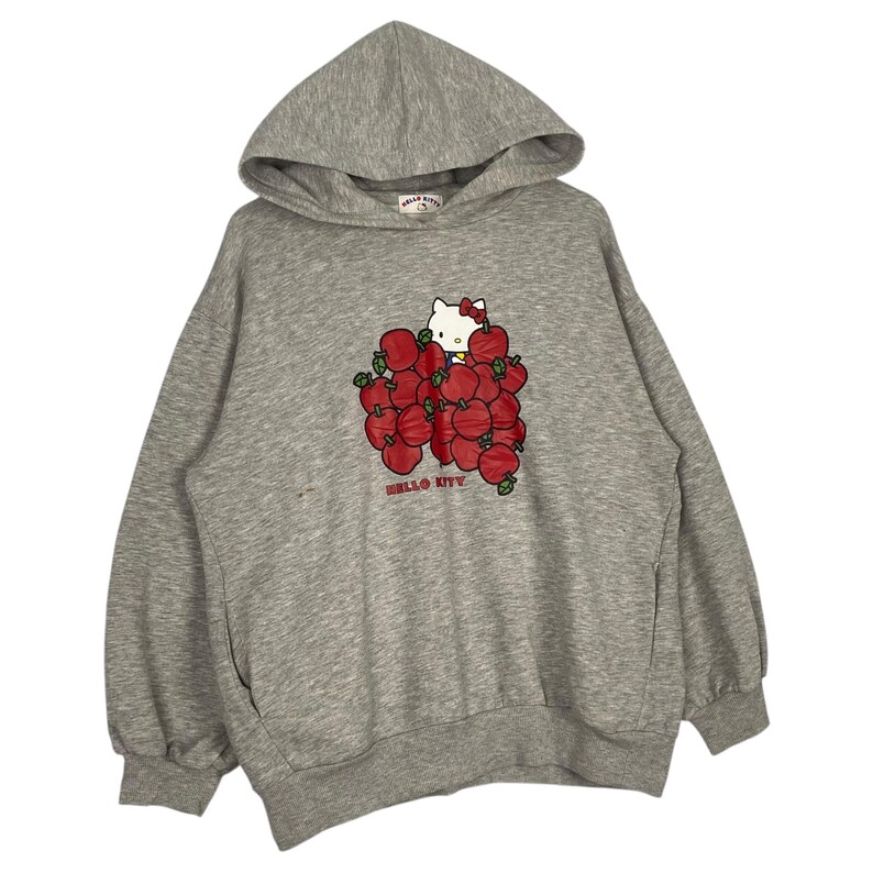 May include: Gray hooded sweatshirt with a Hello Kitty graphic. Hello Kitty is surrounded by red apples and the text "HELLO KITTY" is printed below the graphic.