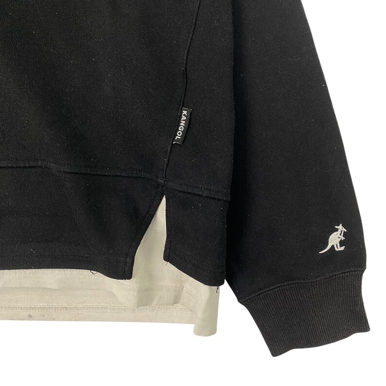 May include: Black sweatshirt with a layered design. The top layer is black, and the bottom layer is a light beige color. The Kangol logo is on the side, and a kangaroo logo is on the sleeve.
