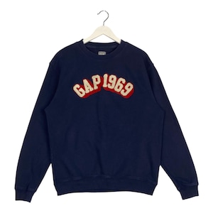 May include: A navy blue sweatshirt with a red and white embroidered logo that says "GAP 1969".