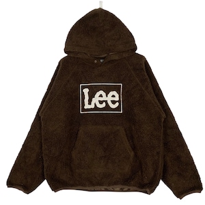 Op de afbeelding: Bruine hoodie met een kangoeroezak en de merknaam "Lee" in een witte doos op de voorkant. De hoodie heeft een zachte, fuzzy textuur en een capuchon met trekkoord. De mouwen zijn lang en de manchetten zijn geribbeld.