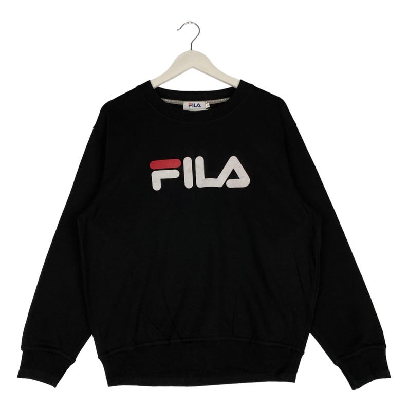 以下が含まれることがあります： 赤いアクセントが付いた白いFILAロゴがついた黒いスウェットシャツ