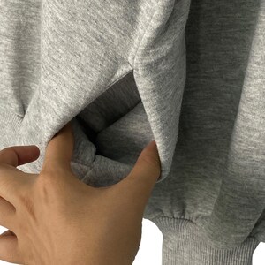 May include: A gray sweatshirt with a pouch pocket on the front. The sweatshirt is made of a soft, comfortable fabric.
