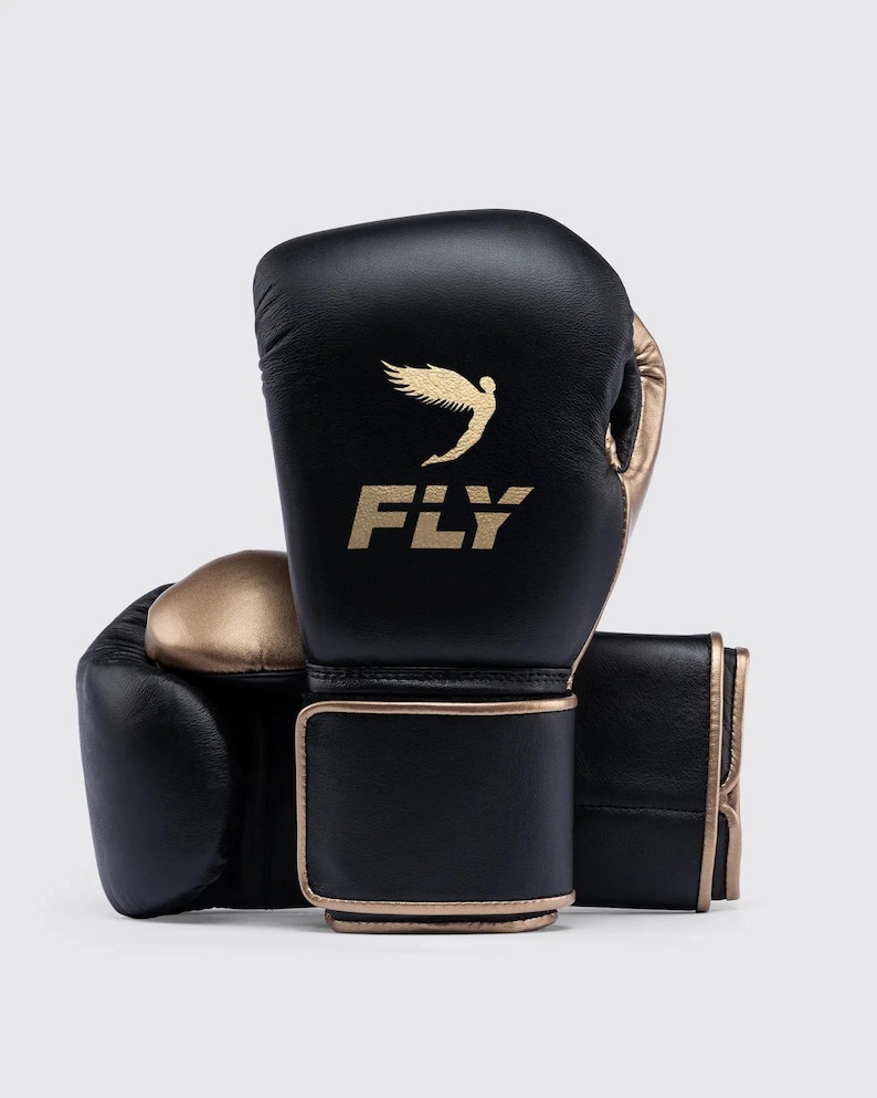 Fly boxing gloves made from premium genuine leather, designed for professional sparring and training sessions. The gloves feature thick multi-layer foam padding for impact protection, secure wrist support with Velcro or lace-up closure, and a comfortable inner lining for extended workouts. Ideal for boxing, bag work, and gym training, offering durability, performance, and a sleek professional fight-style design for men and women athletes.