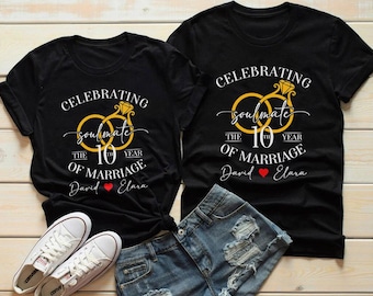 May include: Black t-shirts with a gold ring design and the text "Celebrating soulmate the 10th year of marriage". The shirts also include the names "David" and "Elara" with a heart symbol. White sneakers and denim shorts are also in the image.