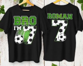 May include: Black t-shirts with soccer-themed graphics. One shirt says "BRO I'M 7" with a soccer ball and the number 7. The other shirt says "ROMAN 7" with a soccer ball and the number 7. Both shirts have green and white accents.