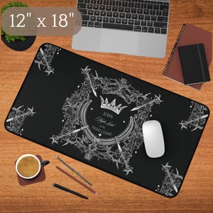 May include: Black rectangular mouse pad, 12 x 18 inches, with a white and gray decorative design featuring a crown, swords, and text. The text reads "John High Lord of the Night Court". A white mouse and a laptop are also visible.